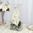 Orchid arrangement in a clear display case on a decorative table setting.