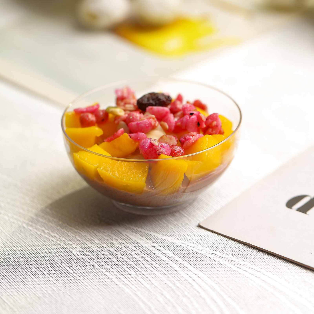 Fruit salad in a glass bowl with mango and pomegranate pieces.