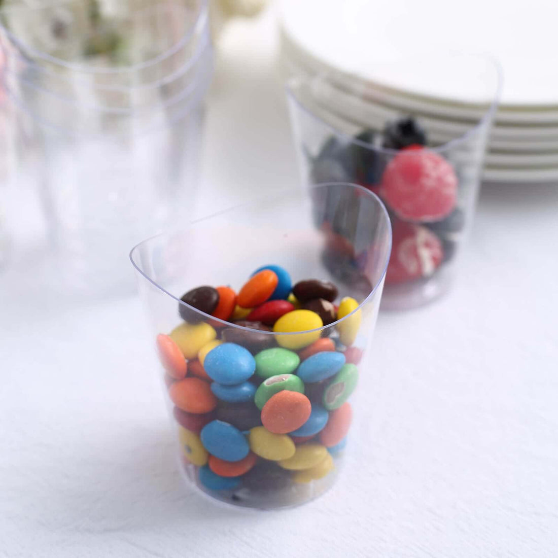 Colorful candies in a clear plastic cup on a white background.