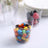 Colorful candies in a clear plastic cup on a white background.