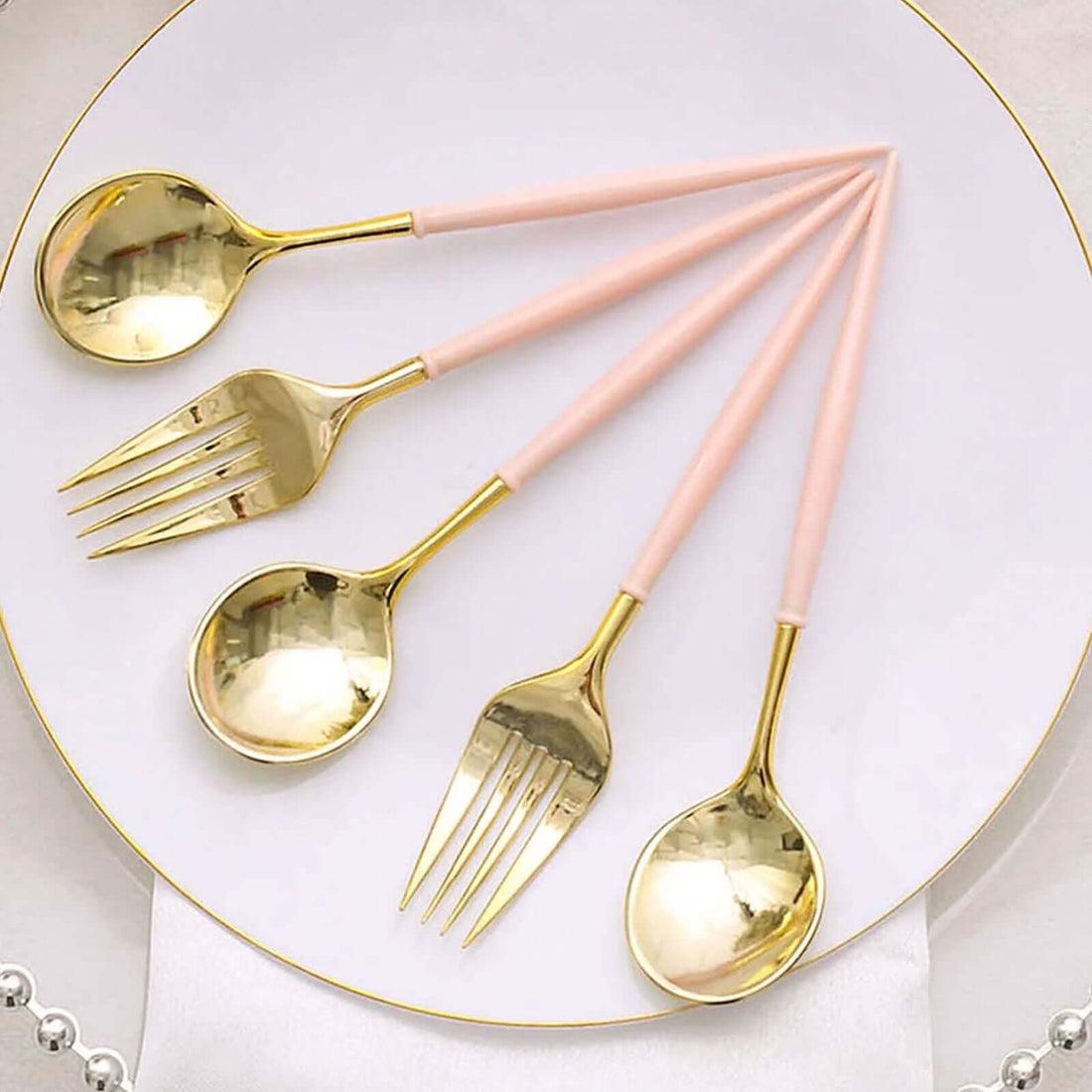 Gold and pink cutlery set on a white plate