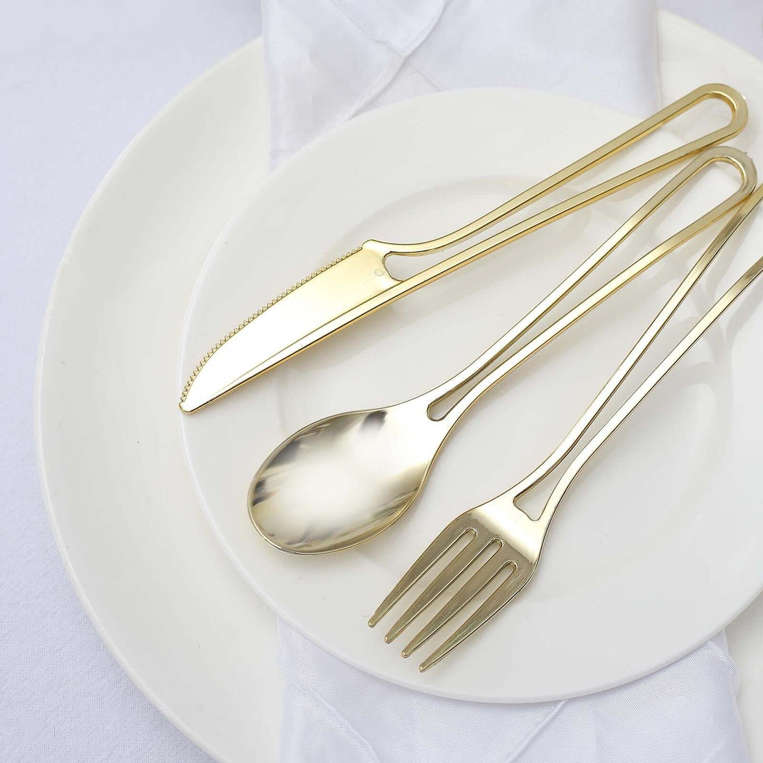 Gold cutlery set on a white plate with a napkin.
