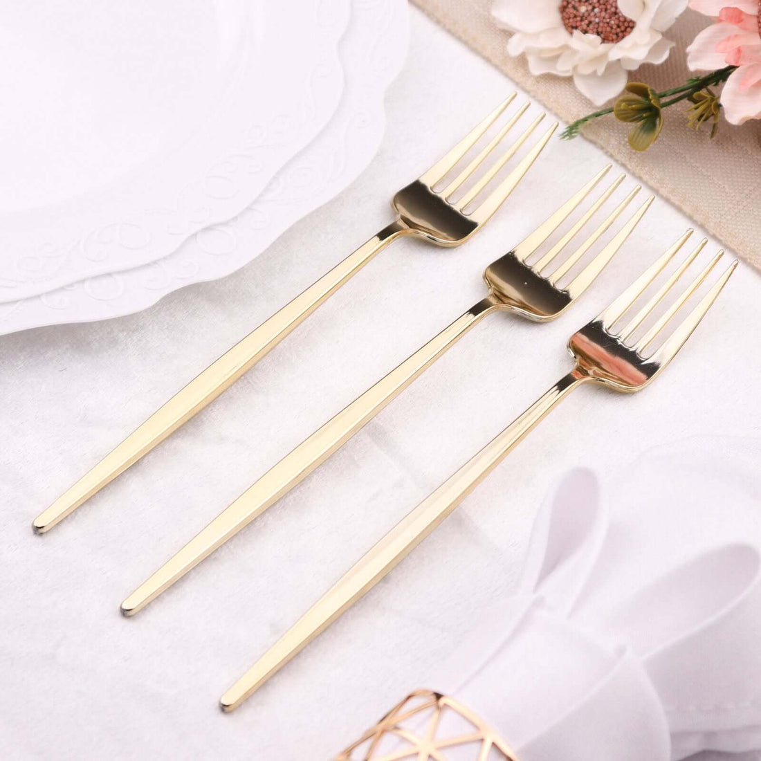 Three elegant gold forks on a table setting with floral accents.