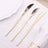 Set of three gold butter knives on a white table setting.