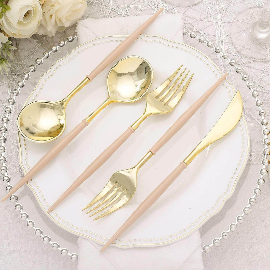Gold cutlery set with pink handles on elegant table setting.
