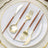 Gold cutlery set with brown handles on a white plate.