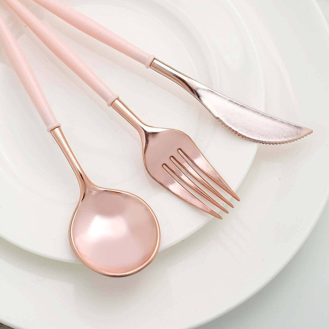 Rose gold cutlery set on white plates.