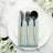 Elegant black and gold cutlery set on a blue napkin atop a white plate.