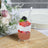 Layered dessert with strawberries, whipped cream, and berries in a glass cup.