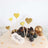 Gold glitter heart cake toppers on a decorated cake with blueberries and decorative balls.