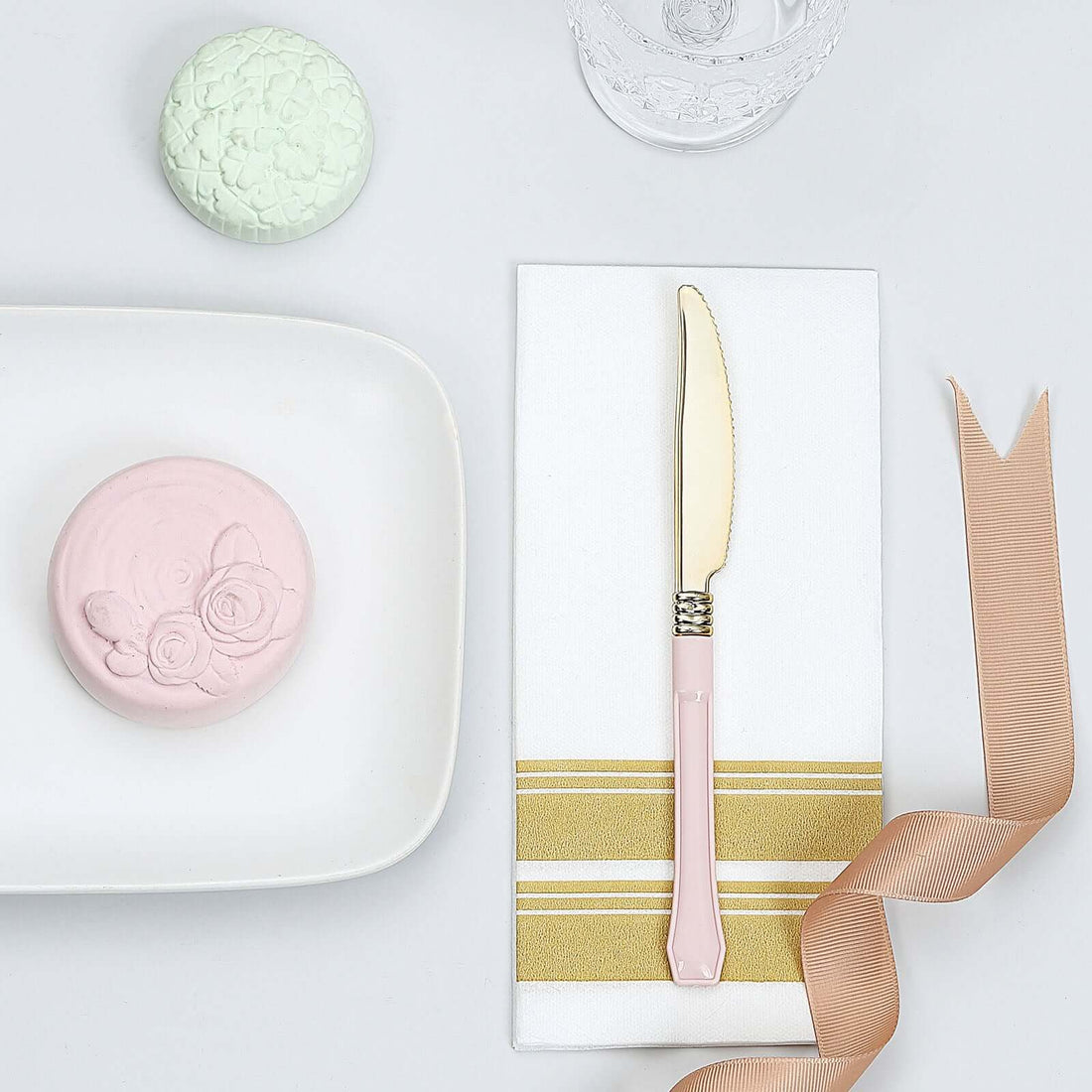 Pastel-colored dessert with knife and ribbon on a table setting.