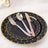 Black dinnerware set with gold polka dots, featuring plates, fork, knife, and spoon.