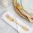 Elegant gold forks on a white napkin and gold-rimmed plate.