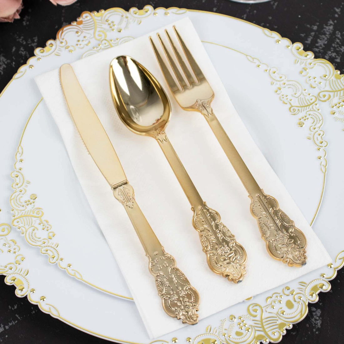 Elegant gold cutlery set on a decorative plate with a napkin.