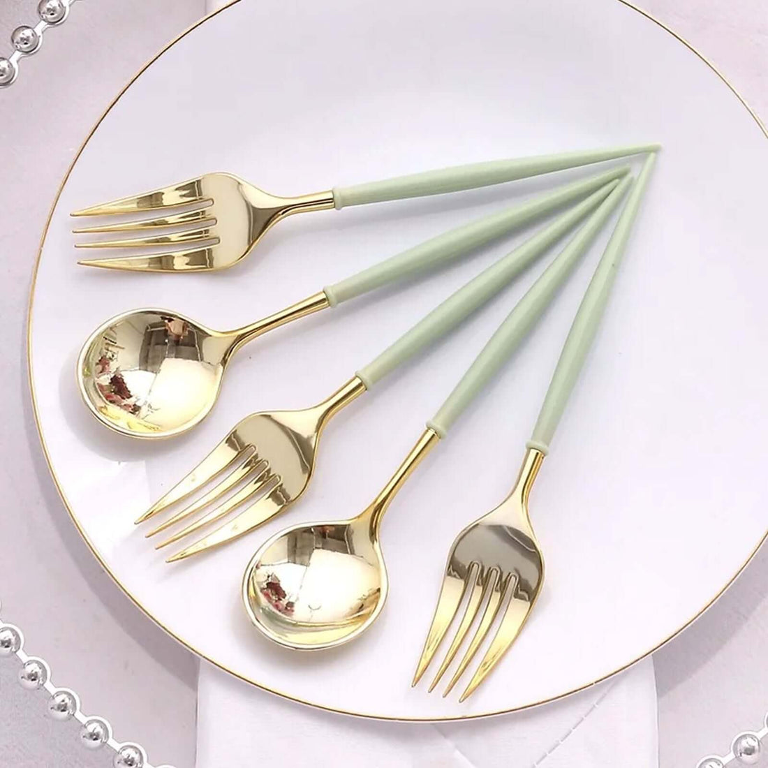 Elegant gold and mint green cutlery set on a white plate.