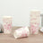 Floral paper cups stacked on a wooden table with one cup tipped over.