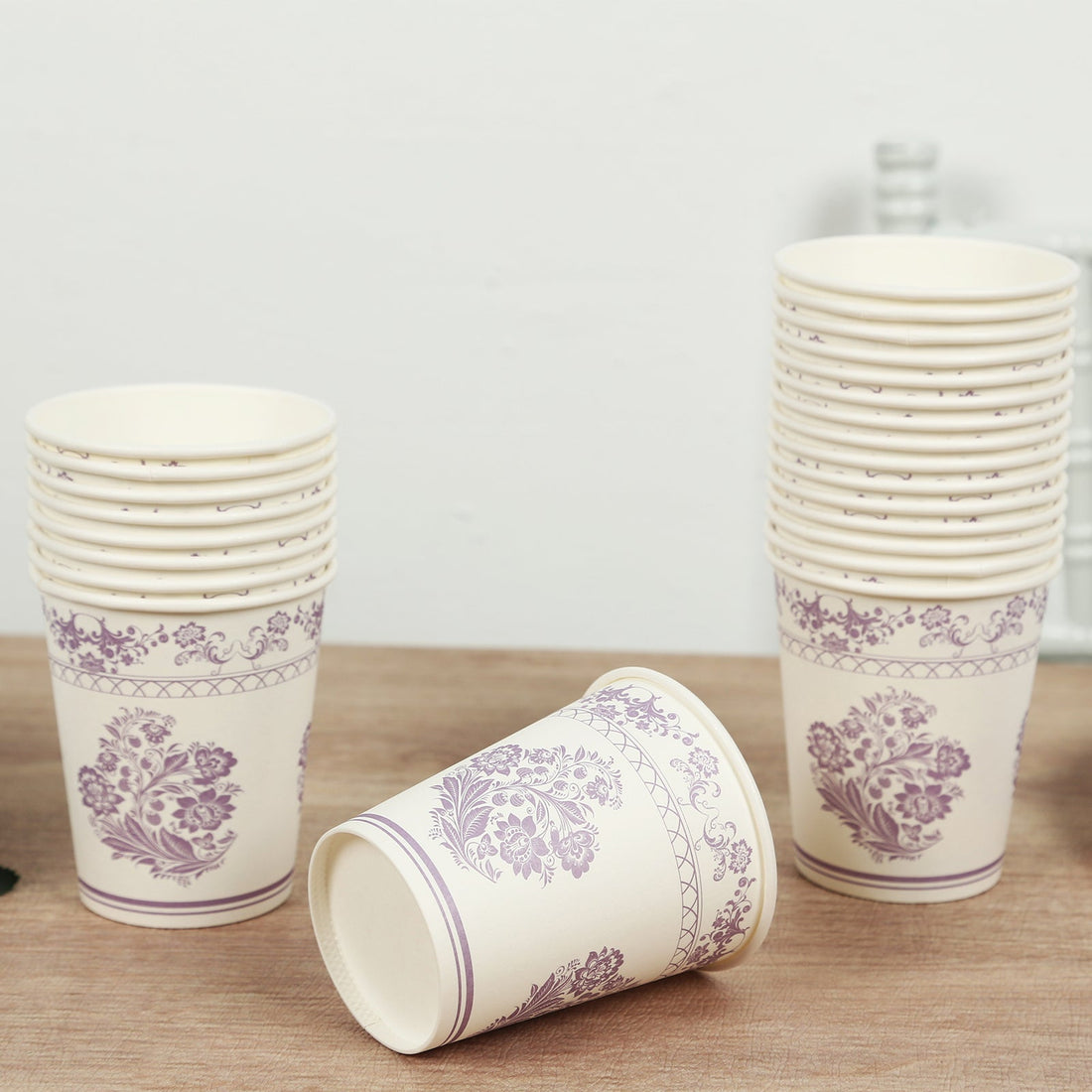 Floral design disposable paper cups stacked on a wooden surface.