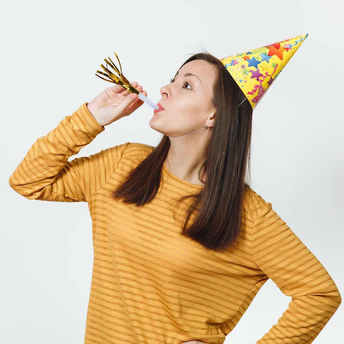 Woman in a party hat blowing a noisemaker, celebrating joyfully.