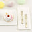 Decorative donut with pink icing and sprinkles on a white plate with forks.