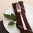 Rose gold fork on a napkin with leaves on a white plate.