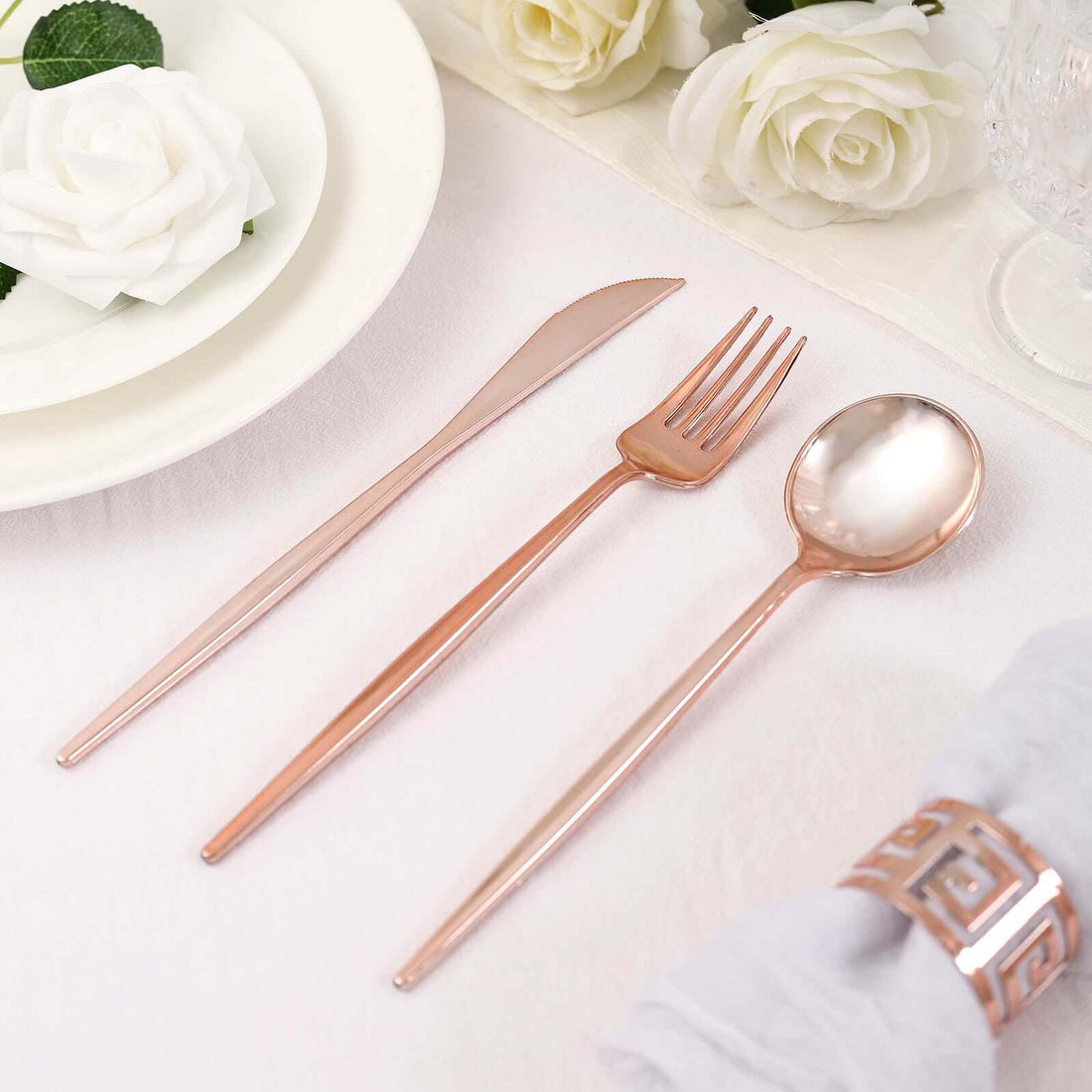 Rose gold cutlery set including knife, fork, and spoon on a table setting.