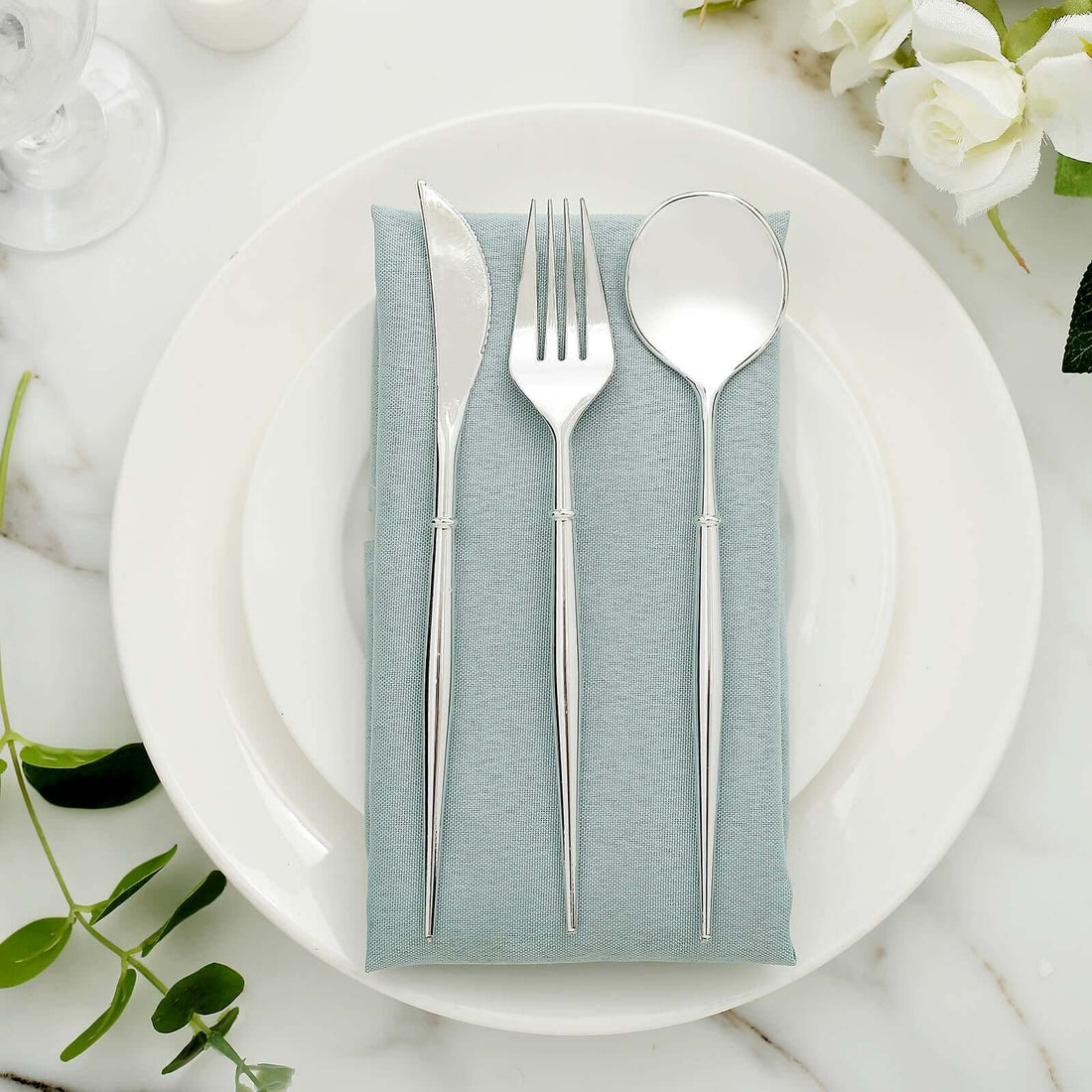 Elegant silver cutlery set on a soft blue napkin atop a white plate.