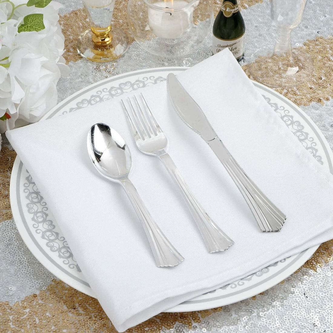 Elegant silver cutlery set on a decorative plate with a napkin.