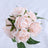 Pink artificial rose bouquet with green leaves on a white background.