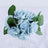Blue rose bouquet with green leaves in a glass vase.
