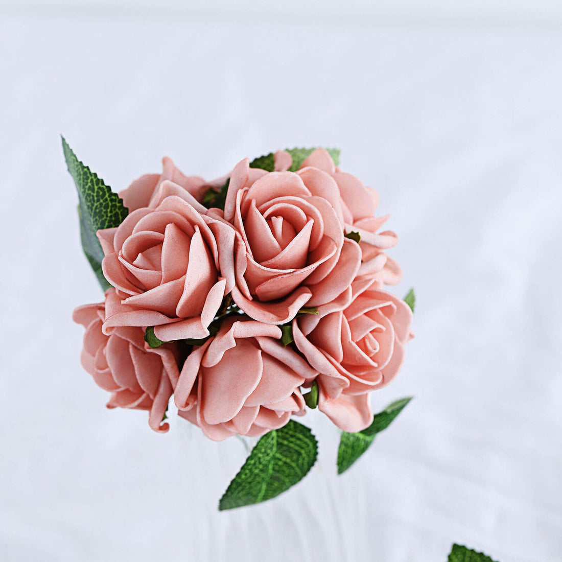 Pink rose bouquet with green leaves on a white background.