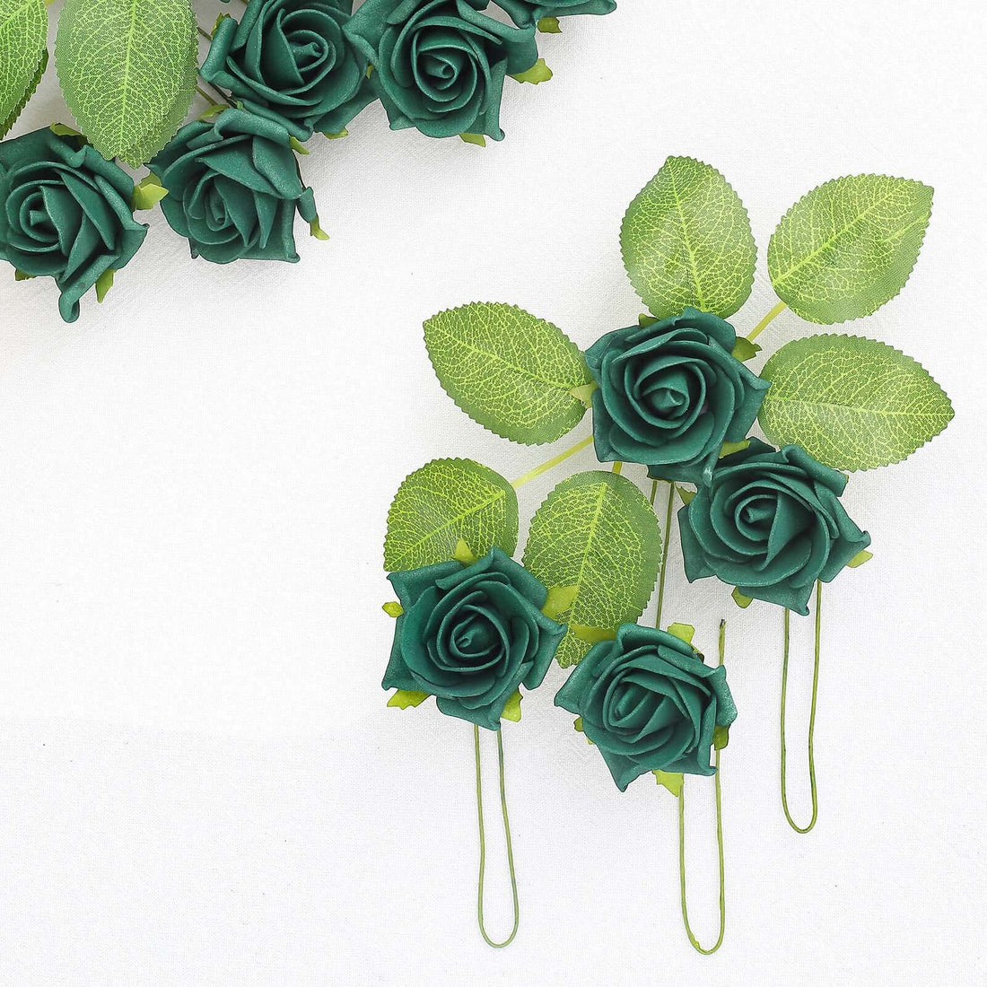 Green artificial roses with leaves on a white background.