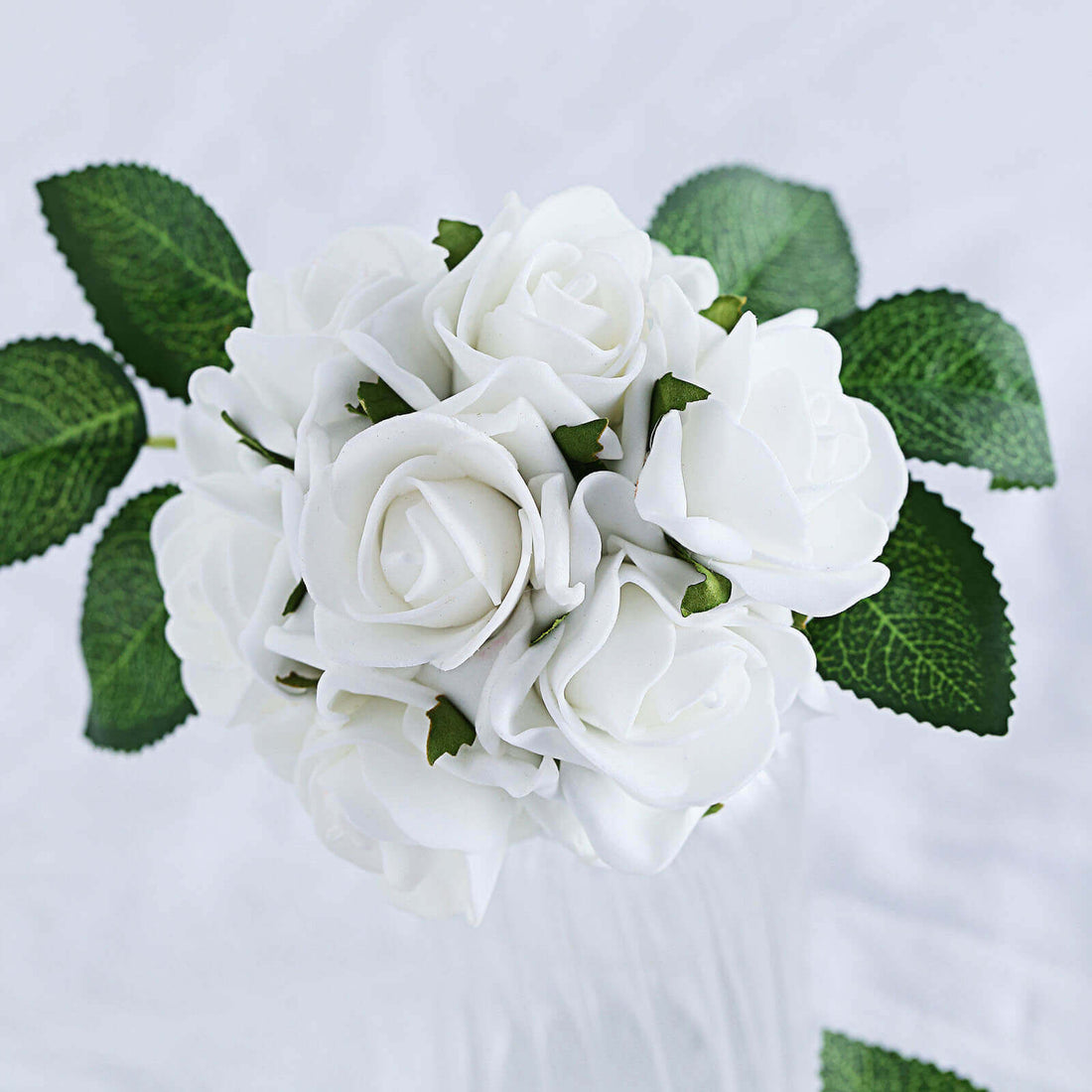 White rose bouquet with green leaves on a plain background