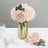 Pink faux roses in a gold vase with decorative accents.