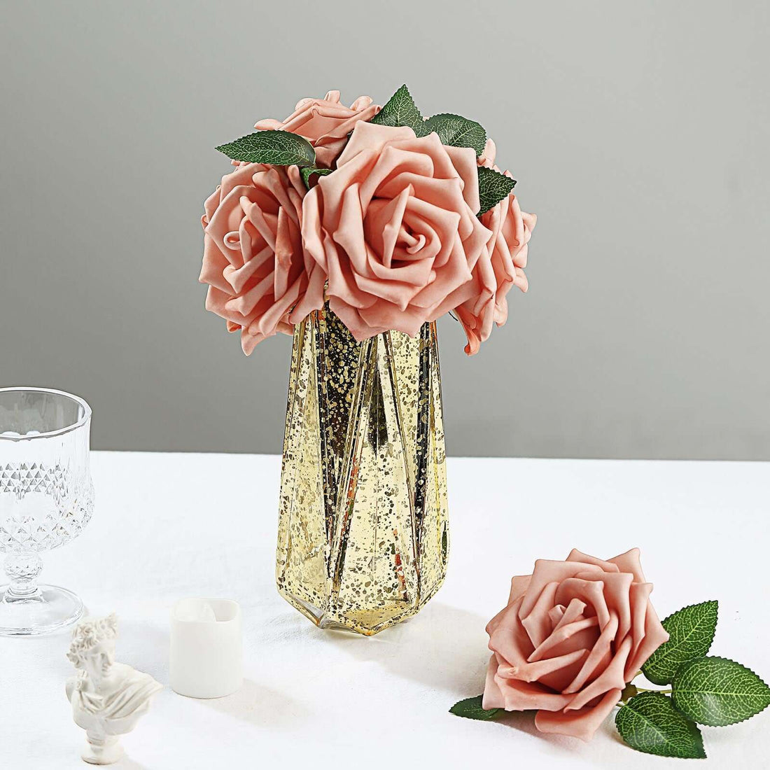Pink rose bouquet in a gold vase on a table.