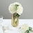 White rose bouquet in a decorative gold vase on a table.
