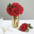 Red roses in a gold vase with a single rose beside it.