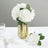 White rose bouquet in a gold vase with green leaves.
