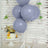 Purple balloons with a birthday cake on a decorative table setting.
