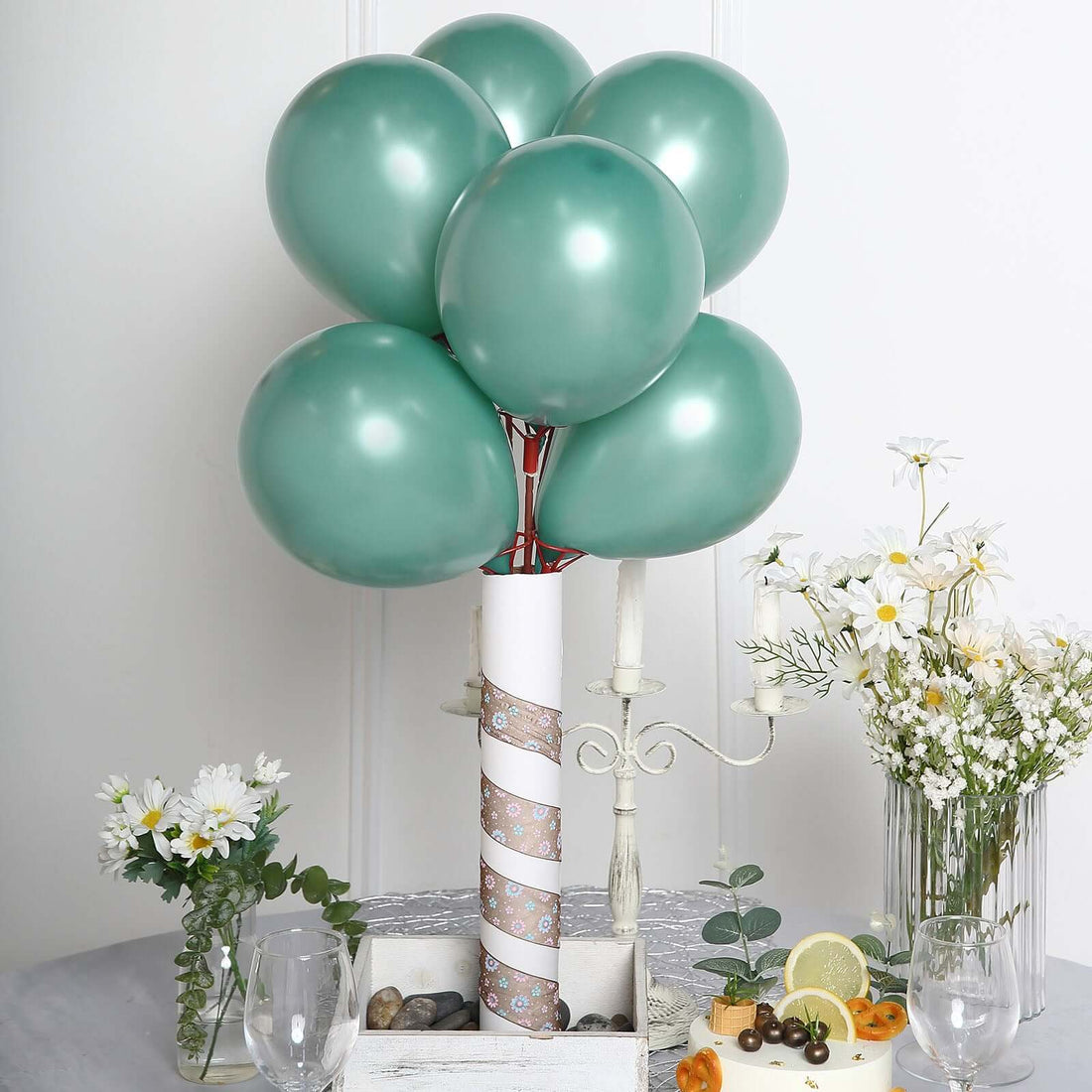 Teal balloons arranged as a decorative centerpiece with flowers and fruit.