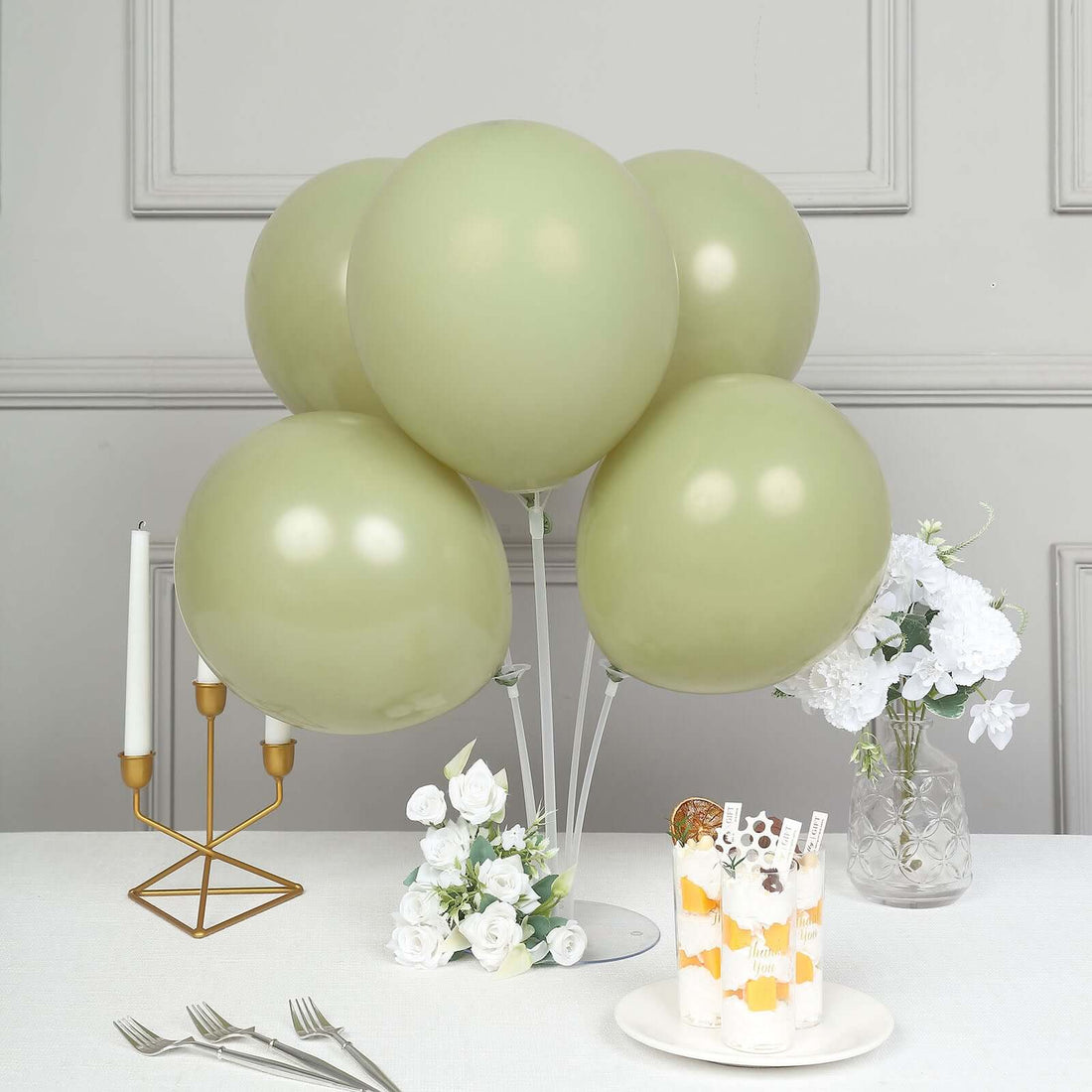Green balloons arrangement with dessert and floral accents in a stylish setting.