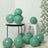 Green decorative balloons arranged around a modern chair and table in a stylish setting.