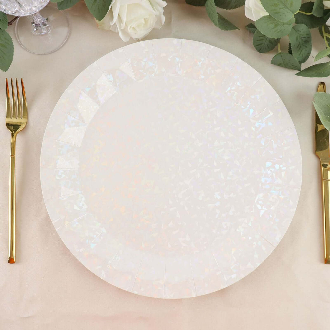 Iridescent disposable plate on a beige table setting with gold utensils.