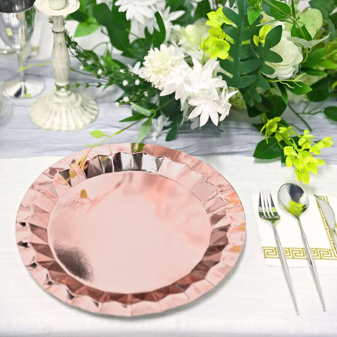 Rose gold paper plate on a beautifully set dining table with floral decorations.