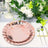Rose gold paper plate on a beautifully set dining table with floral decorations.