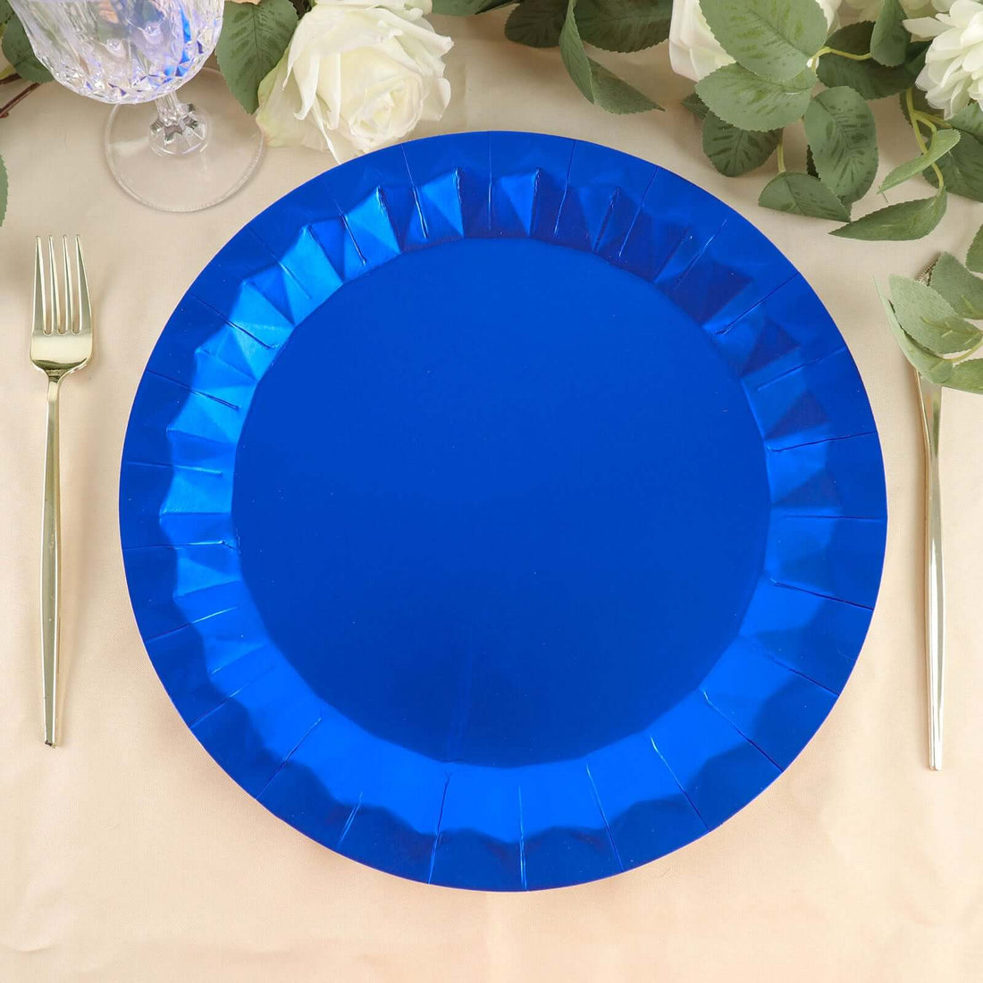 Blue disposable plate on a table setting with cutlery and floral decor.