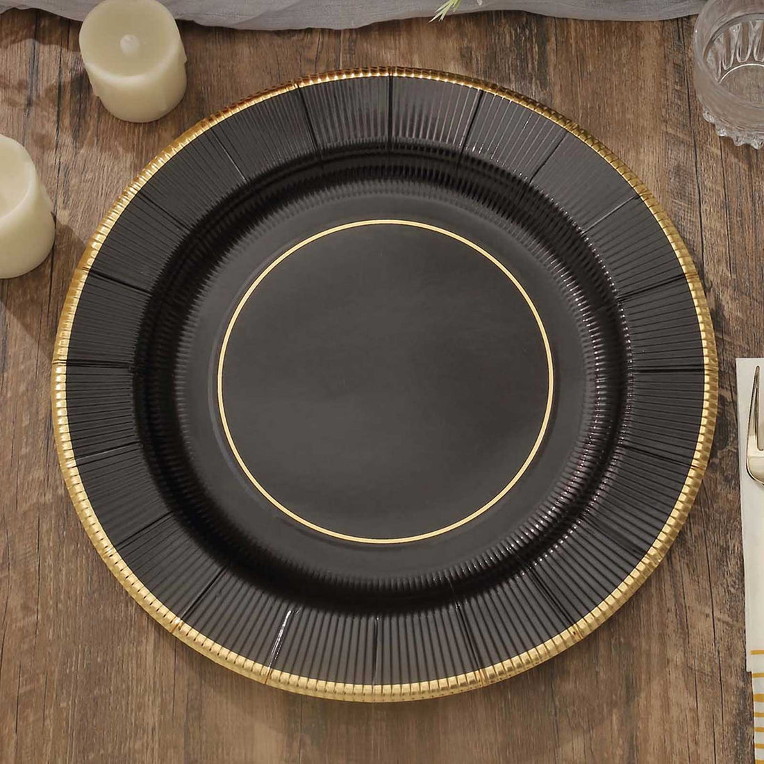 Black decorative charger plate with gold trim on a wooden table.