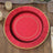 Red decorative plate with gold trim on a wooden surface.