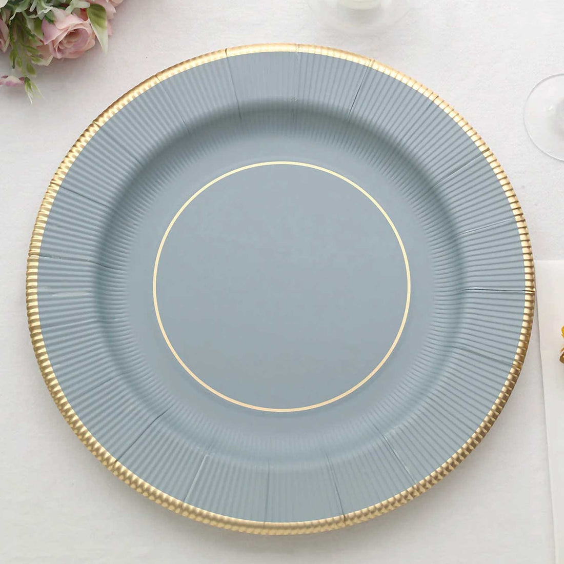 Round blue plate with gold trim on a white table setting.