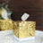 Gold glitter gift box with a ribbon on a white plate.
