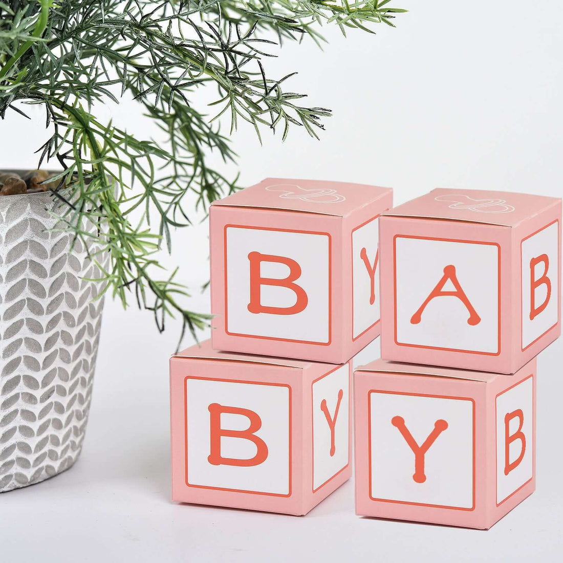 Colorful baby blocks stacked beside a potted plant.